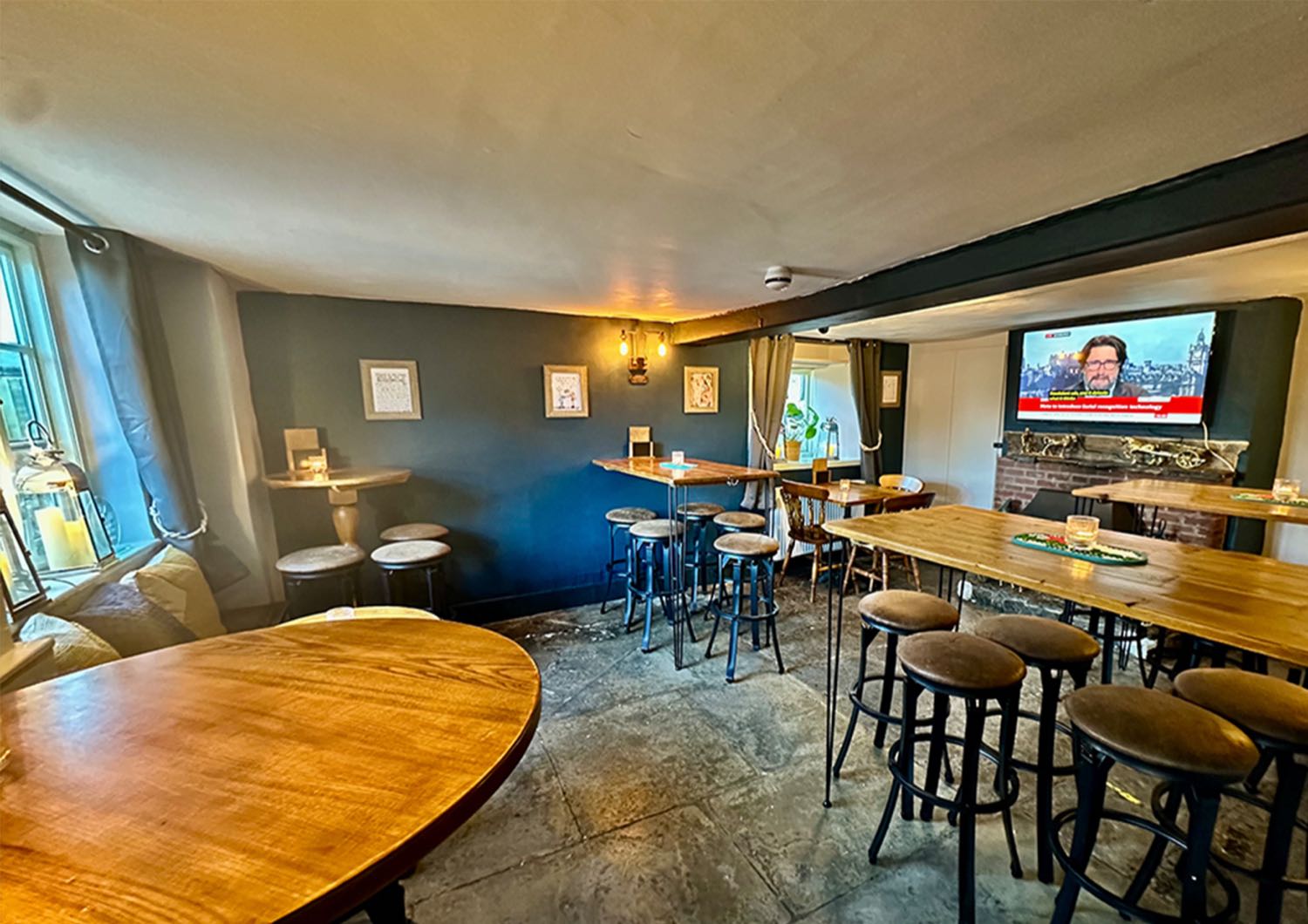 The dining room at The Cottage of Content - stone floors, a blue-painted wall and tables under the beams.